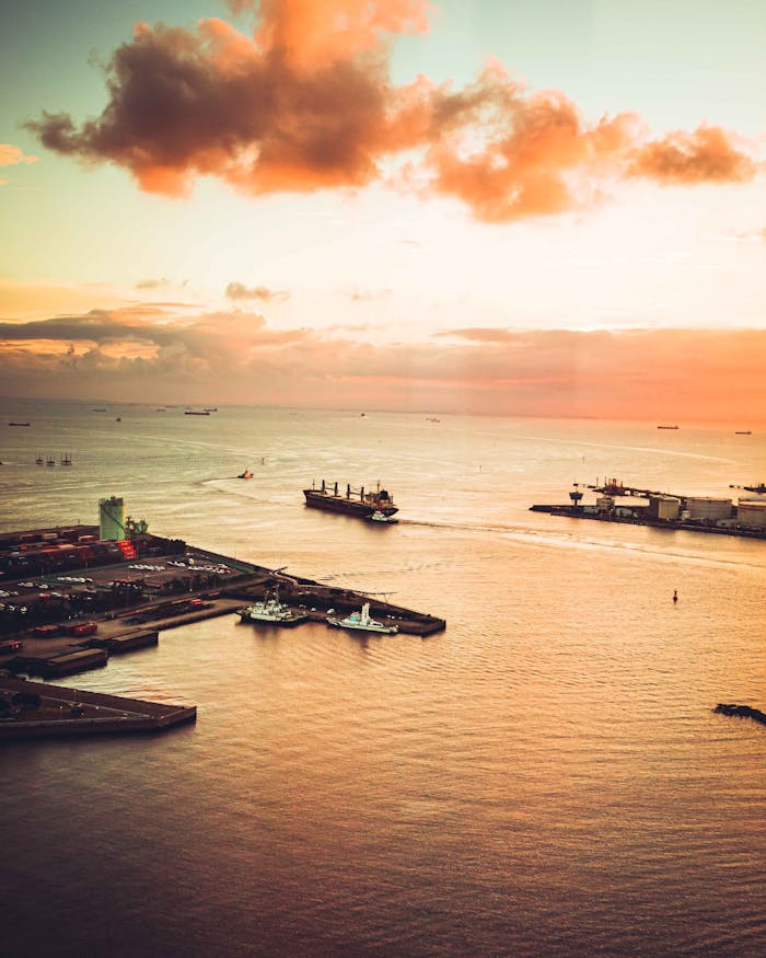 Captivating aerial view of Chiba Harbor in Japan during sunset with cargo ships and vivid clouds.