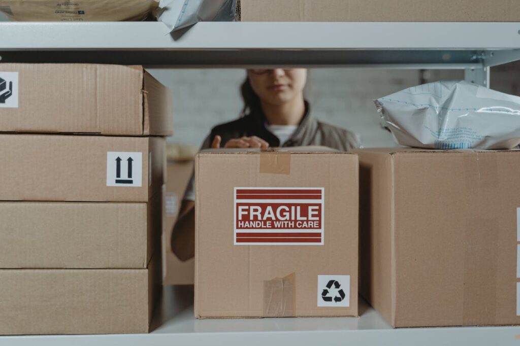 A person organizing fragile cardboard boxes in a warehouse setting.
